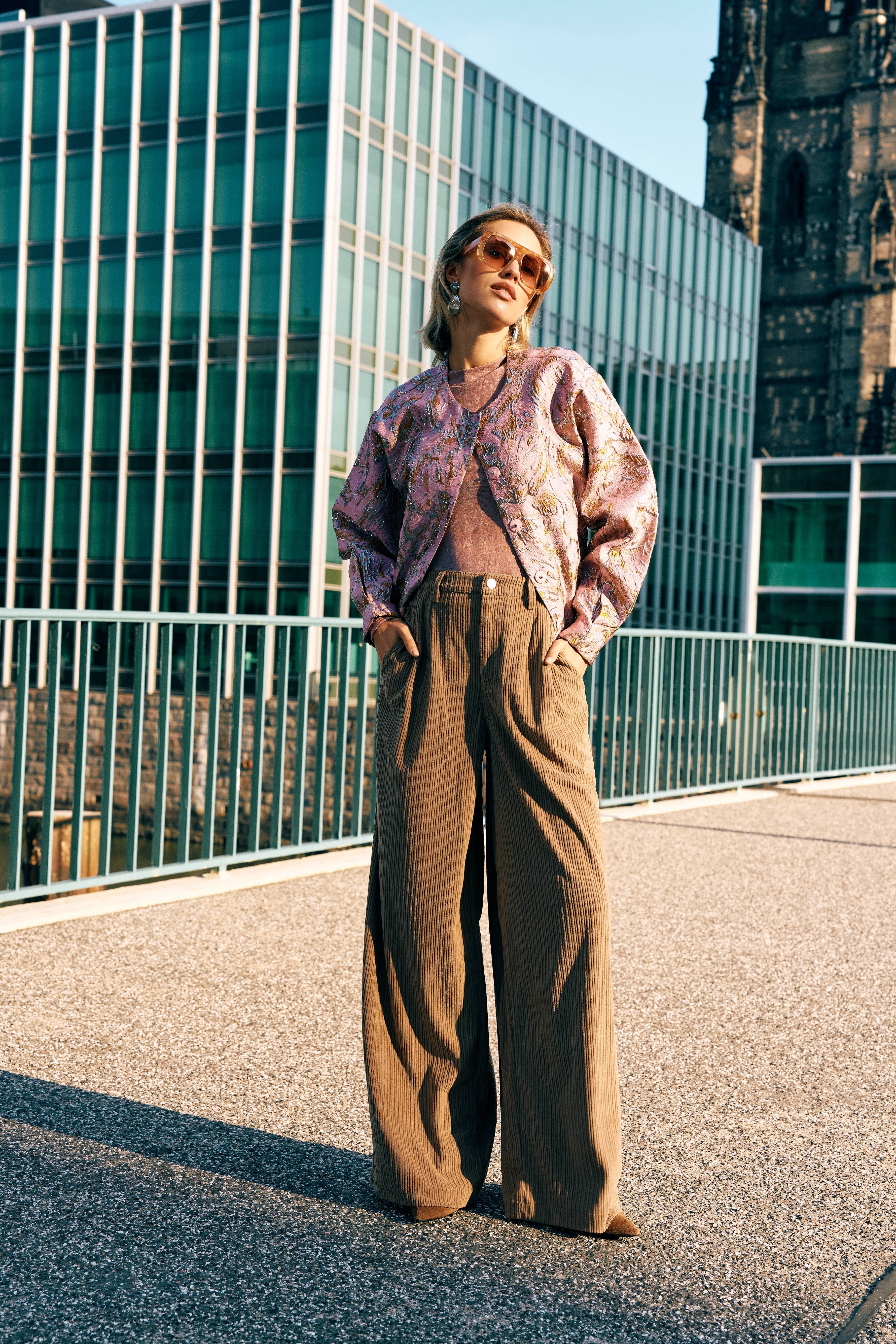 Campagnefoto: model in roze jacquard bomberjack Jules met bruine wijde pantalon in de stad | Jo&Co Club
