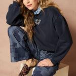 Broek Inoa - Denim Patchwork mid blue – model draagt de wijde patchwork broek met een donkerblauwe trui. | Jo&Co Club