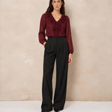Model in ruche blouse Lofty Manner Kio met wijde zwarte broek, voorkant | Jo&Co Club