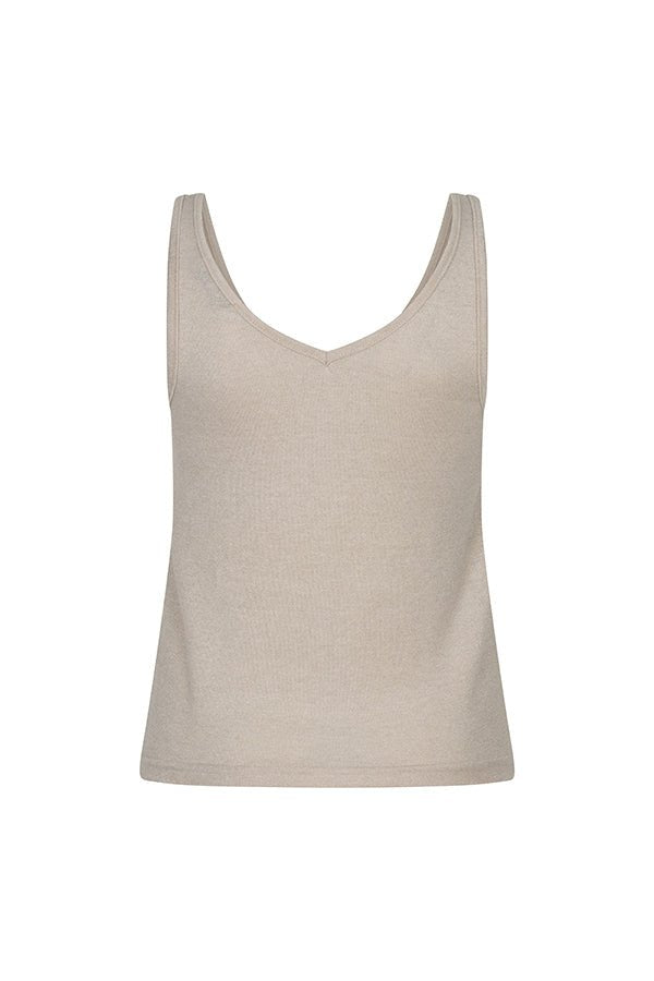 Een model met bruin krullend haar staat tegen een effen, beige achtergrond | Lofty Manner Nicki | Jo&Co Club