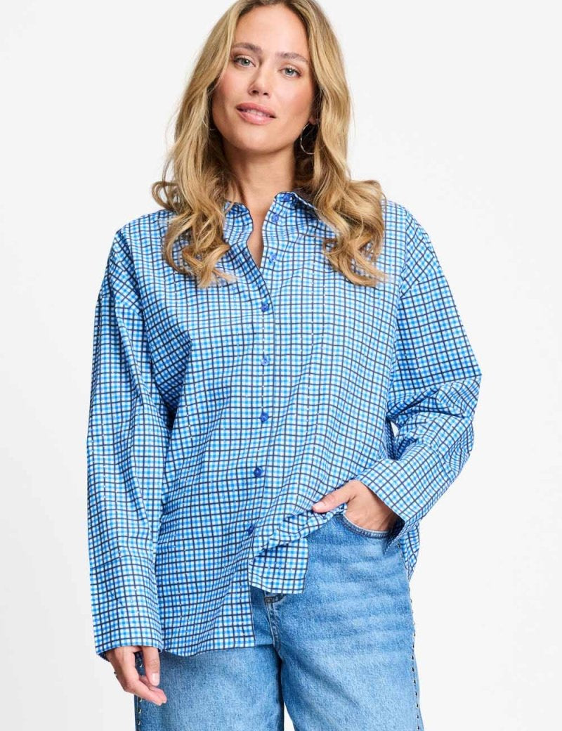 Model draagt de saffierblauwe geruite Beau Check blouse van POM Amsterdam op een lichtblauwe jeans.