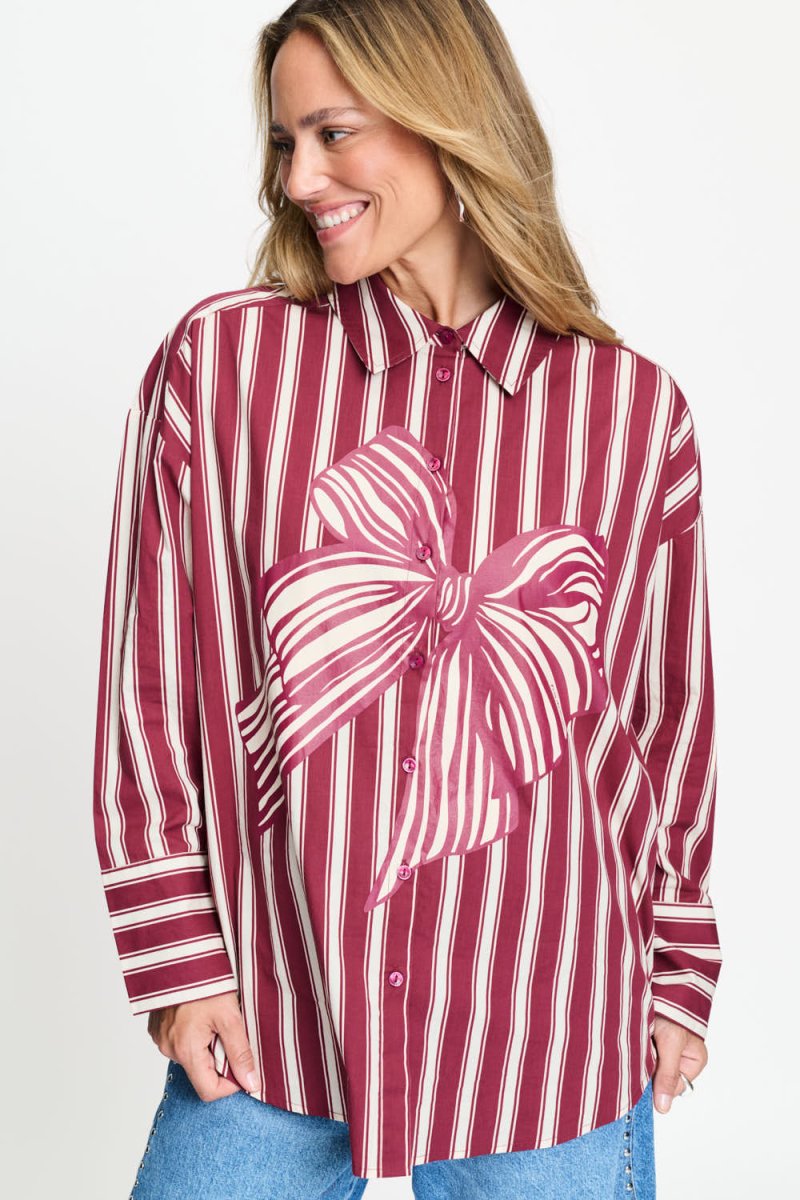Gestreepte blouse met overhemdkraag en roze strikprint, van dichtbij op de voorkant gefotografeerd.