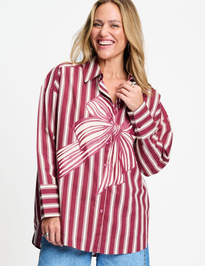 Model draagt de donkerrood gestreepte Beau Ribbon blouse van POM Amsterdam met grote strikprint.