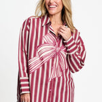 Model draagt de donkerrood gestreepte Beau Ribbon blouse van POM Amsterdam met grote strikprint.