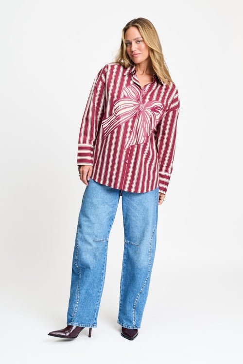 Volledige look met de gestreepte blouse los gedragen op een lichtblauwe wijde jeans.