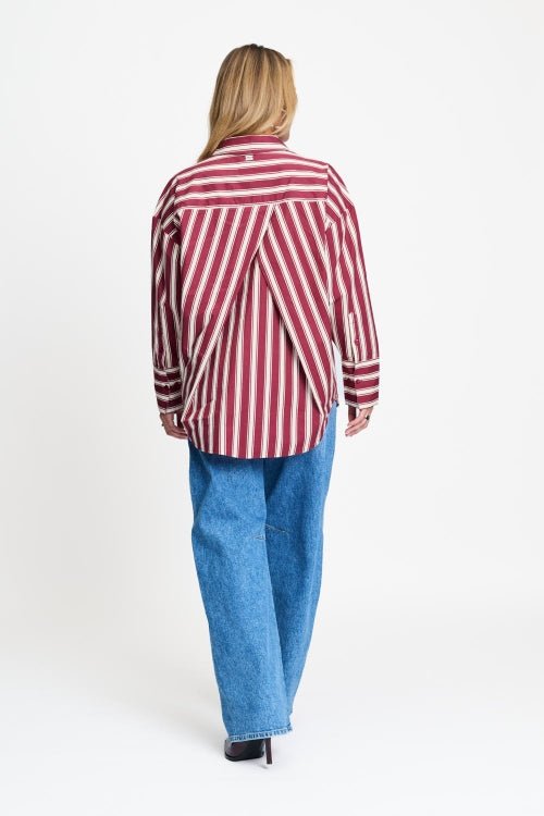 Achterkant van de rood gestreepte blouse met verlaagde schouders en langer achterpand.