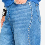 Detailfoto van de zilverkleurige studs langs de zijnaad van de jeans.