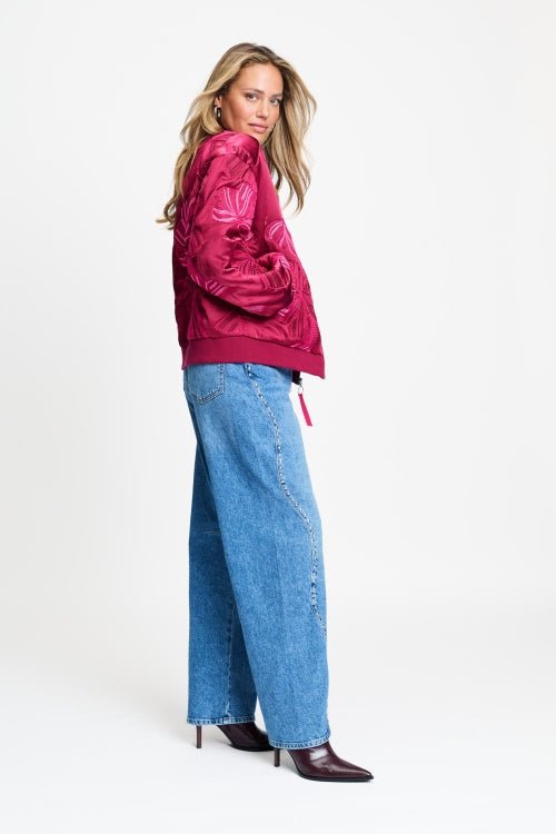 Volledige look met de bomberjas op een wijde lichtblauwe jeans en donkere laarzen.