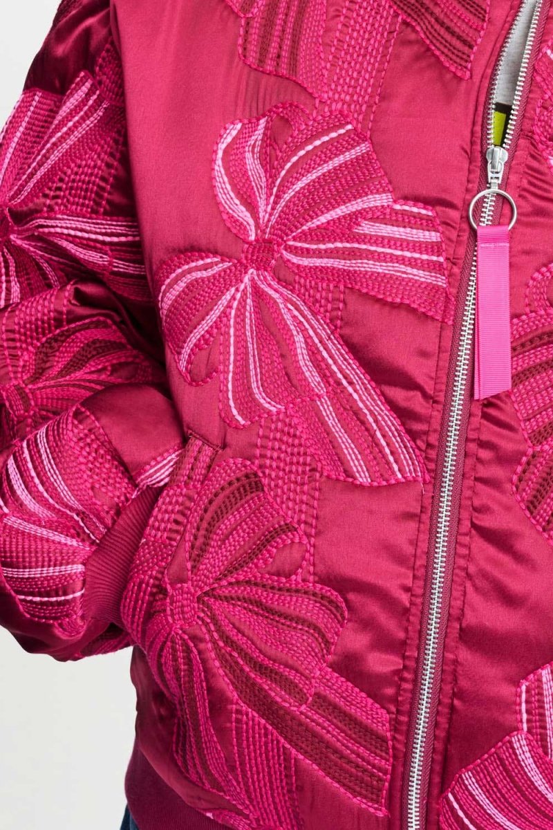 Detailfoto van het strikborduursel en de rits met roze lintje op de bomberjas.