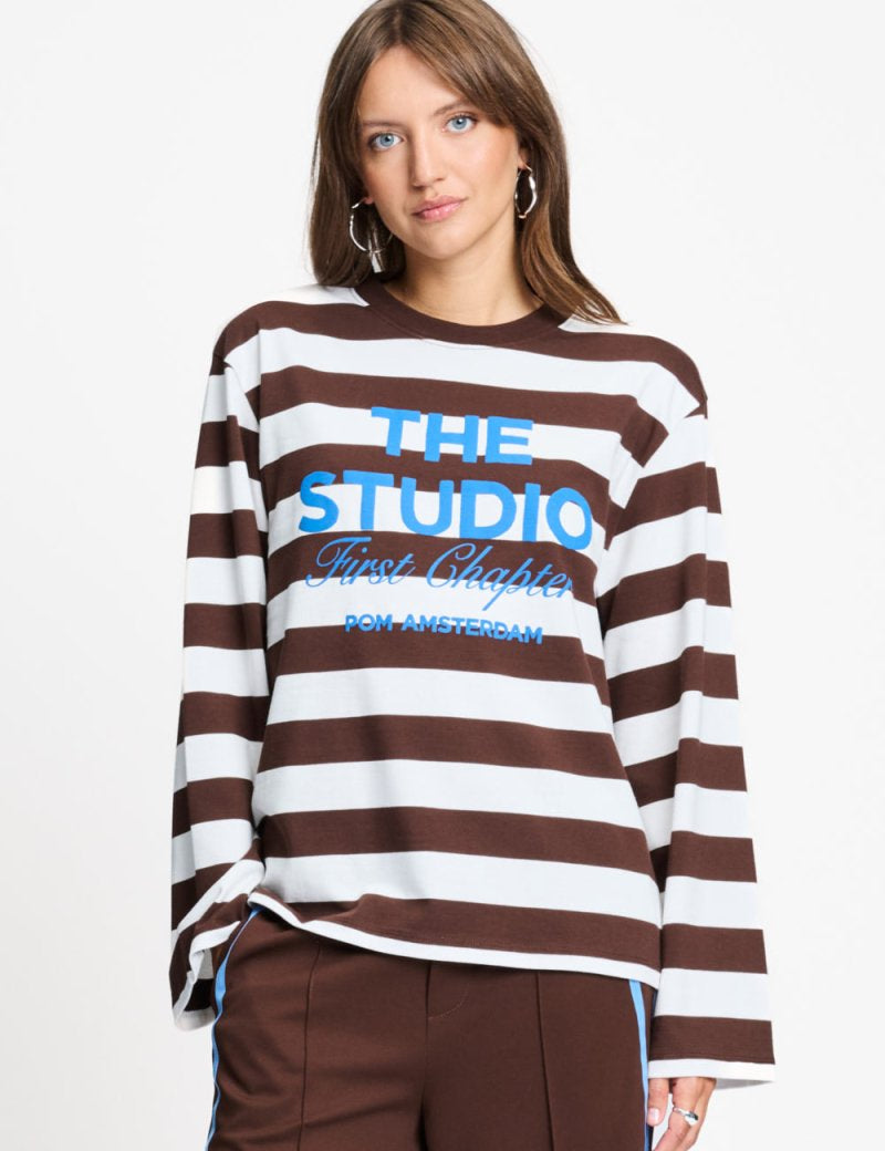 Model draagt de bruin met witte gestreepte longsleeve van POM Amsterdam met blauwe print.