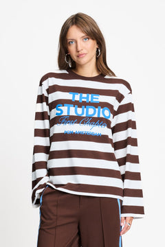 Model draagt de bruin met witte gestreepte longsleeve van POM Amsterdam met blauwe print.