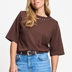 Model draagt het chocoladebruine t-shirt Taylor van POM Amsterdam op een lichte jeans.