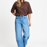 Volledige look met het bruine t-shirt op een wijde lichtblauwe jeans.