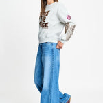 Volledige look met de grijze sweater op een wijde lichtblauwe jeans.