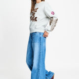 Volledige look met de grijze sweater op een wijde lichtblauwe jeans.