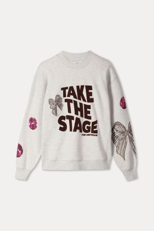 Productfoto van de grijze sweater plat gefotografeerd, met tekstprint en pailletdetails.