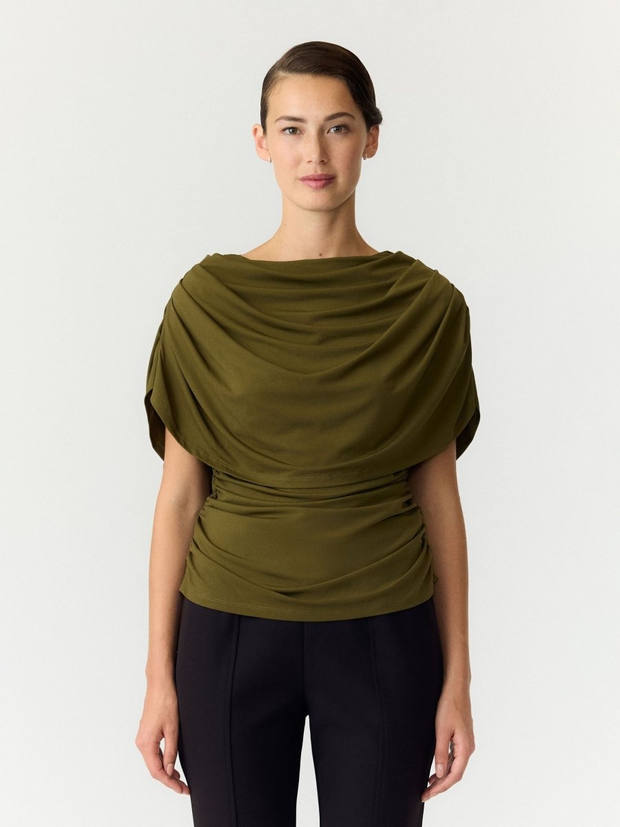 Cape top Y.A.S Drala in olijfgroen – model met boothals en gedrapeerde cape, op een zwarte pantalon | Jo&Co Club