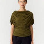 Cape top Y.A.S Drala in olijfgroen – model met boothals en gedrapeerde cape, op een zwarte pantalon | Jo&Co Club