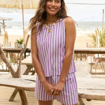 Model draagt de Ydence Mima short en Arlette top als co-ord set met paars-witte strepen tijdens een zomerse dag op het strandterras.