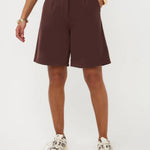 Een model, zichtbaar vanaf de taille, draagt een wijdvallende, donkerbruine bermuda short | Ydence Jolijn | Jo&Co Club