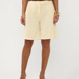Close-up taille tot knie van soft yellow bermuda met hoge tailleband en plooien | Ydence Jolijn | Jo&Co Club
