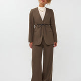 model draagt de ydence lexie blazer in de kleur mud met een zwart ceintuur. hieronder draagt ze de yade pants van ydence.