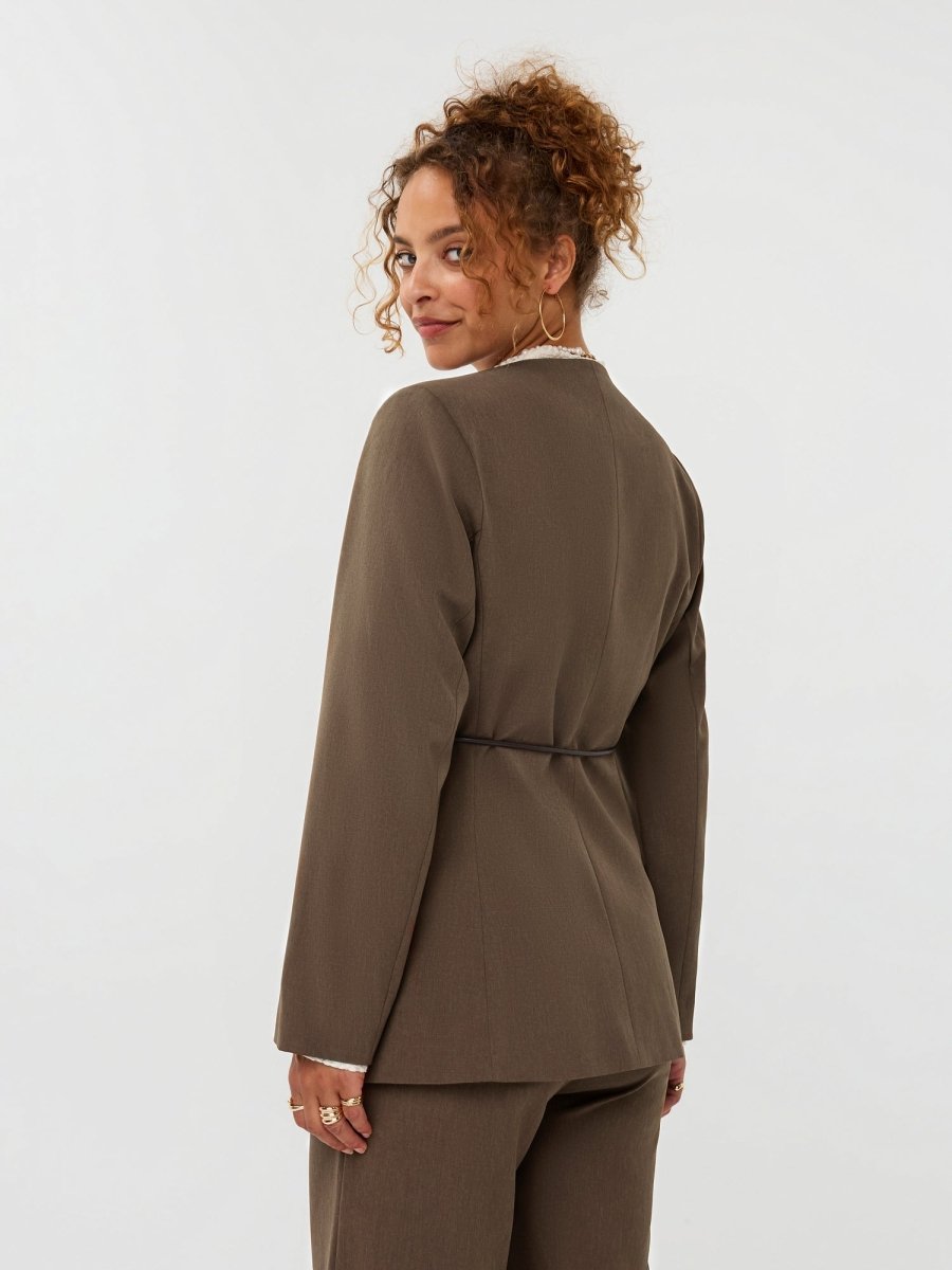 model draagt de ydence lexie blazer in de kleir mud met een zwart ceintuur, achter aanzicht.
