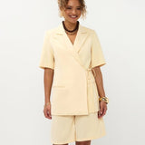 Model lachend frontaal in soft yellow Ydence Blazer Lucille met bermuda short als setje | Jo&Co Club