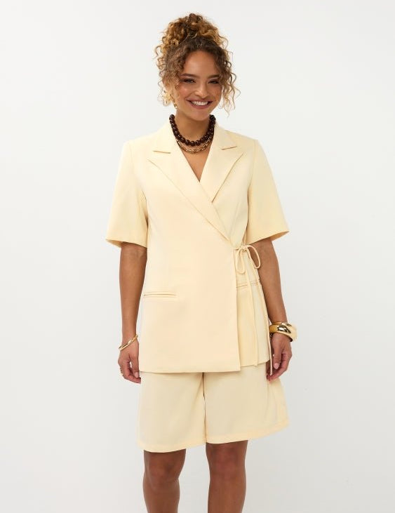 Model lachend frontaal in soft yellow Ydence Blazer Lucille met bermuda short als setje | Jo&Co Club