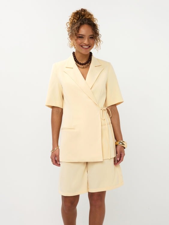 Model lachend frontaal in soft yellow Ydence Blazer Lucille met bermuda short als setje | Jo&Co Club