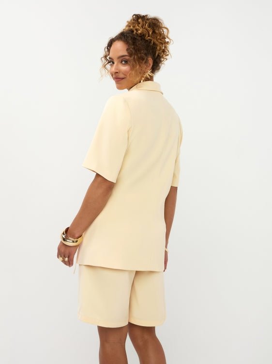 Achteraanzicht model in soft yellow Ydence Blazer Lucille met strikceintuur op de zijkant | Jo&Co Club