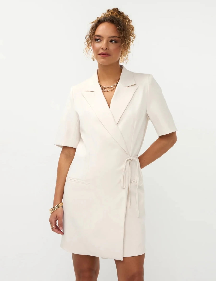 Een model met opgestoken krullend haar presenteert een gebroken witte blazerjurk met korte mouwen | Ydence Hazel | Jo&Co Club