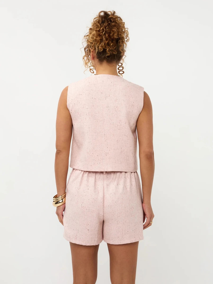 Een model, van achteren gefotografeerd, draagt een lichtroze, tweed-achtige tweedelige set | Ydence Amanda | Jo&Co Club