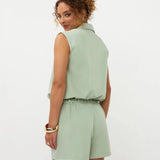 Een model, van achteren gefotografeerd, draagt een lichtgroene mouwloze playsuit met een fijne | Ydence Jeanie | Jo&Co Club