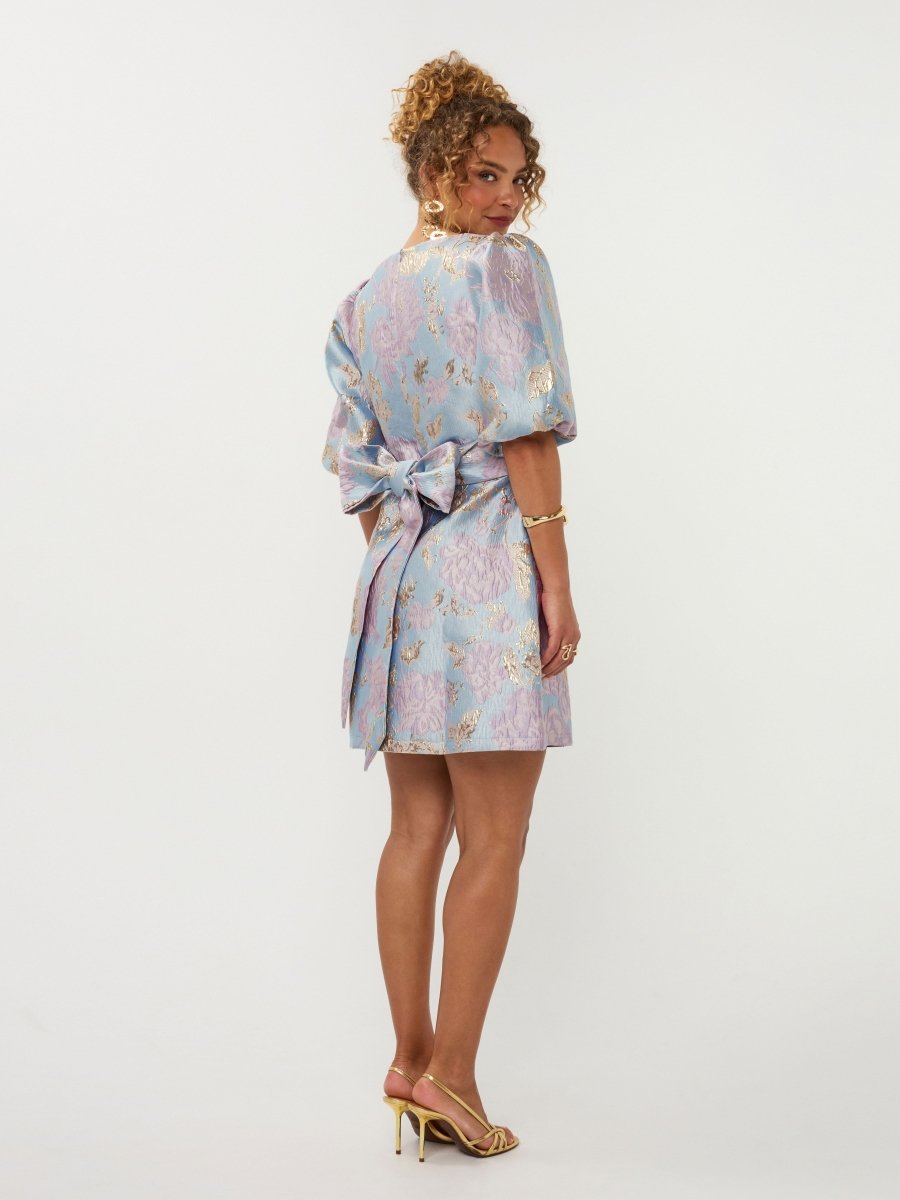 Een model, van achteren gefotografeerd, draagt een jacquard mini-jurk in lichtblauw | Ydence Charmaine | Jo&Co Club