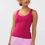 Model draagt de Ydence top Leny, een mouwloze gebreide top in felroze kleur, gestyled met een gestreepte short.