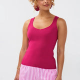 Model draagt de Ydence top Leny, een mouwloze gebreide top in felroze kleur, gestyled met een gestreepte short.