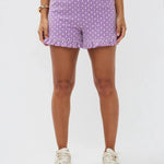 Model draagt de Larissa short, een paarse luchtige short met wit bloemenpatroon en rucherand van Ydence.