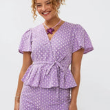 Model draagt de larissa short en de Milay top, een broderie wikkelblouse met korte mouwen en strikceintuur van Ydence.
