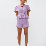 Model draagt de Ydence Milay top en Larissa short, een paarse co-ord set in broderie stijl met bloemmotief en ruches.
