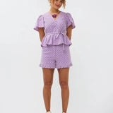 Model draagt de Ydence Milay top en Larissa short, een paarse co-ord set in broderie stijl met bloemmotief en ruches.