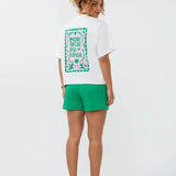 Model draagt het Ydence T-shirt More Amore met opvallende rugprint in roze en groen met de tekst 'More Amore Por Favor'.