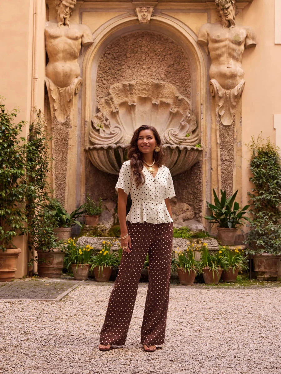 Een vrouw poseert in een sfeervolle, Italiaans aandoende binnenplaats voor een sierlijke stenen | Ydence Stacey | Jo&Co Club