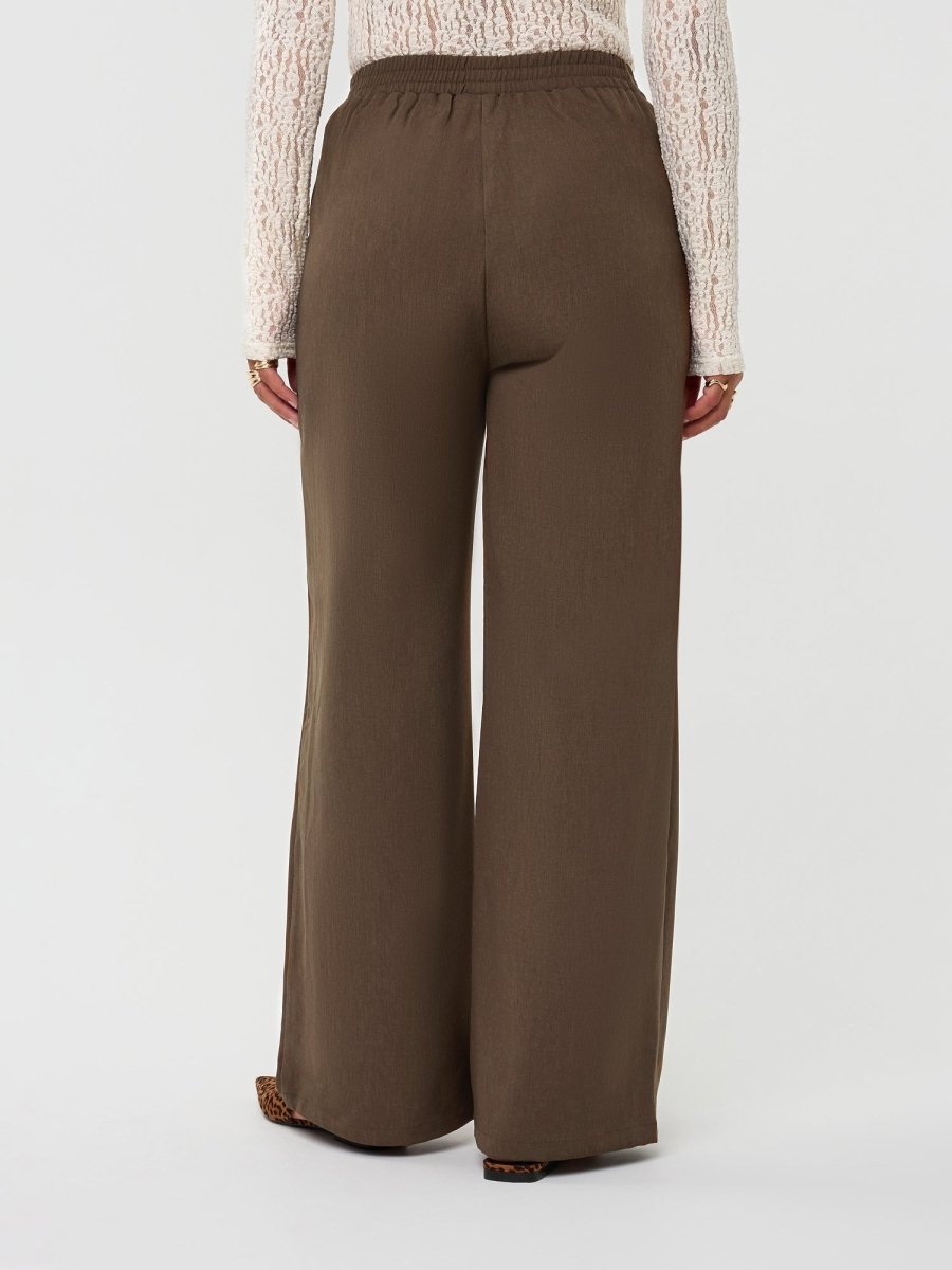 Model draagt de yade pants van ydence in de kleur mud, achter aanzicht.