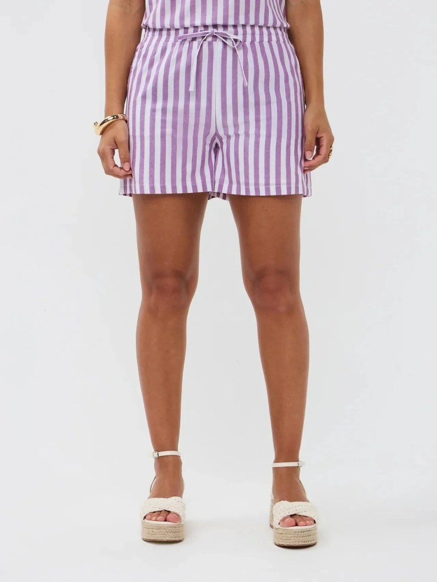 Model draagt de Mima short, een lila-wit gestreepte linnen short met strikceintuur van Ydence.