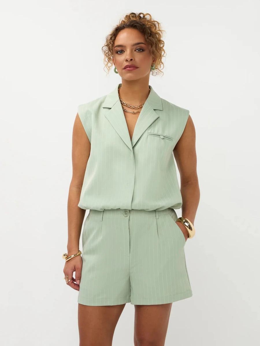 Een model poseert in een lichtgroene, pinstripe tweedelige set tegen een witte achtergrond | Ydence Sibel | Jo&Co Club