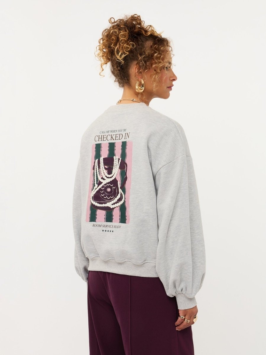 Model in grijze sweater met hartje en print op de rug Ydence Checked In | Jo&Co Club