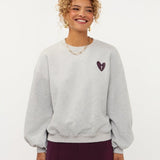 Model in grijze sweater met hartje en print op de rug Ydence Checked In | Jo&Co Club