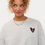 Campagnebeeld Ydence winter 2026: grijze sweater met hartje en print op de rug Ydence Checked In | Jo&Co Club