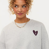 Campagnebeeld Ydence winter 2026: grijze sweater met hartje en print op de rug Ydence Checked In | Jo&Co Club